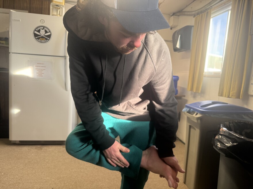 At the Yukon River Bridge checkpoint, Fairbanks musher Jonah Bacon gives a status update about his big toe, which is still healing up from frostbite he sustained earlier in the Yukon Quest Alaska 750. (Patrick Gilchrist/KUAC)