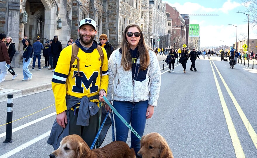Tom and Rachelle Hawley smile with their dogs, all in Michigan gear.