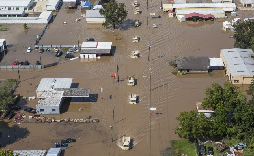 National Guard vehicles drive down a flooded street in Wharton, Texas, on Friday.