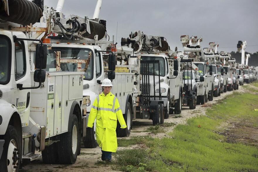 Heather Danenhower, with Duke Energy, walks around utility trucks that are staged in a rural lot in The Villages of Sumter County, Fla., Wednesday, Sept. 28, 2022. Hurricane Ian rapidly intensified as it neared landfall along Florida's southwest coast Wednesday morning, gaining top winds of 155 mph (250 kph), just shy of the most dangerous Category 5 status. 