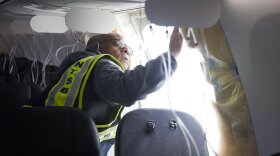Investigator-in-Charge John Lovell examines the hole where a door plug blew out of Alaska Airlines Flight 1282 Boeing 737-9 MAX. (NTSB)