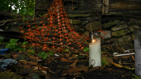 A candle burns in the backyard of an abandoned home where the remains of child were found in Connecticut. Under a new state law adopted in 2024, DCF must release certain information about children who die or nearly die due to abuse or neglect when requested.