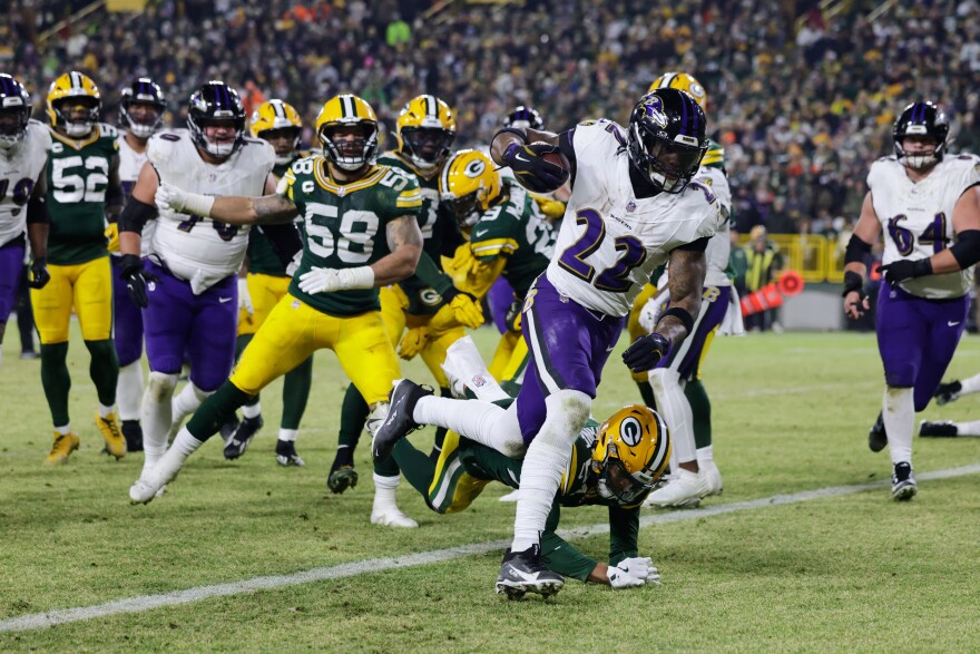 Baltimore Ravens running back Derrick Henry (22) scores a touchdown past Green Bay Packers cornerback Carrington Valentine (24) during the first half of an NFL football game, Saturday, Dec. 27, 2025, in Green Bay, Wis. (AP Photo/Matt Ludtke)