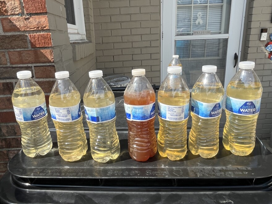 A row of water bottles with varying shades of discolored water in them including one that is opaque.