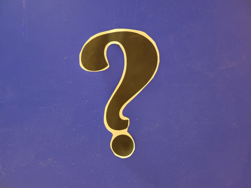 Black question mark with white border against a blue background