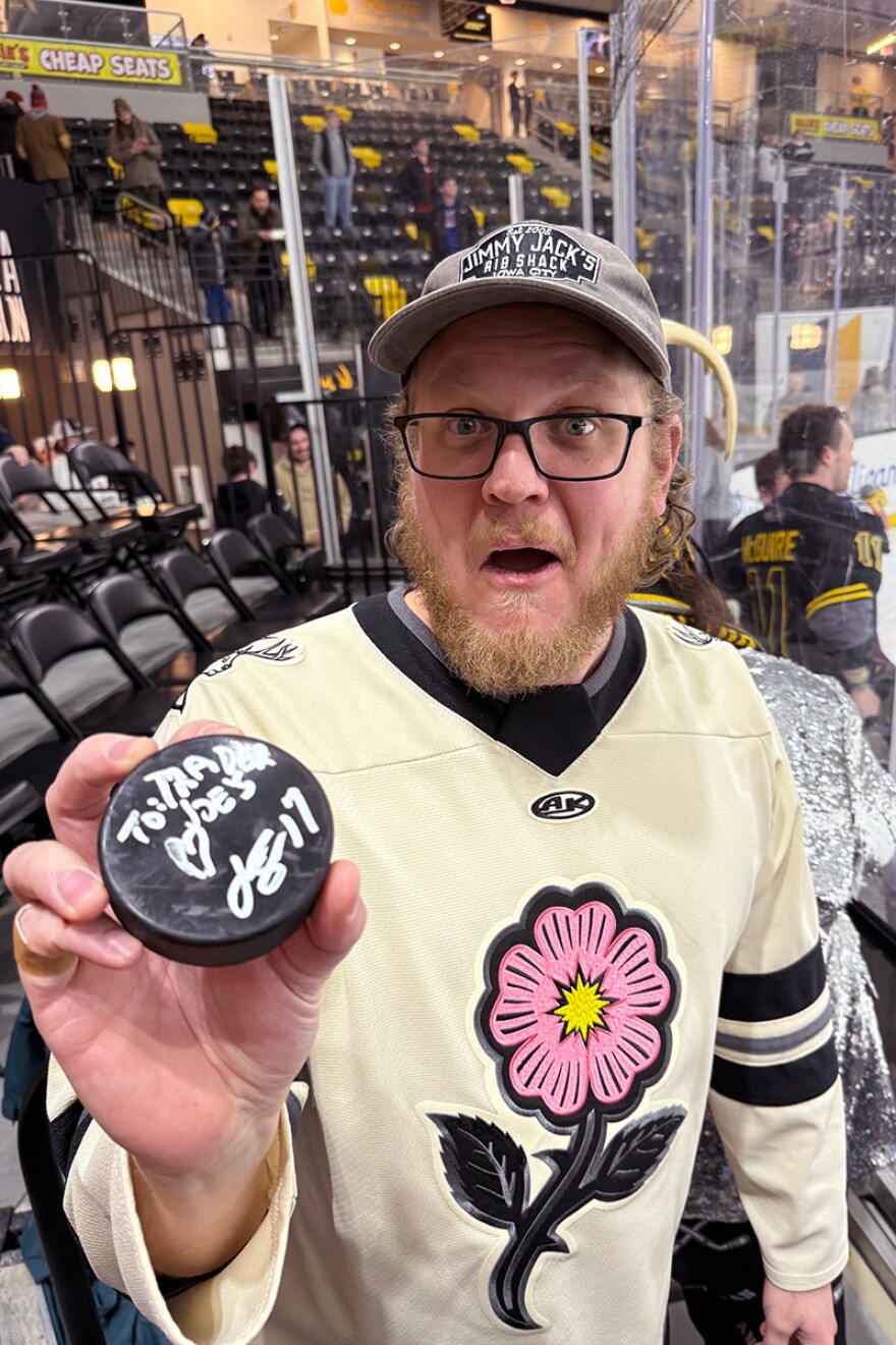 Colin Underwood holds up a signed hockey puck. 