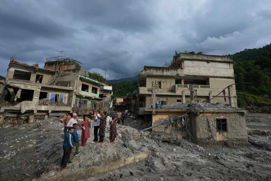 Residents and others look at damaged structures after flash flooding in the Devighat area of the Nuwakot district in Nepal, Friday, Aug. 28, 2026. (AP Photo/Rajesh Kumar Singh)
