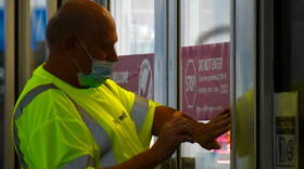 A worker at a Pilot Travel Center gas station in Greenfield, Indiana puts a stick on the door telling patrons not to enter if they feel symptoms associated with COVID-19.
