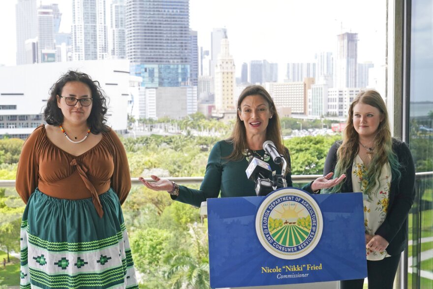 Florida Commissioner of Agriculture and Consumer Services Nikki Fried, center, speaks during a news conference along with youth climate leaders, Valholly Frank, left, and Delaney Reynolds, right, Thursday, April 21, 2022, at the Phillip & Patricia Frost Museum of Science in Miami. Fried unveil a proposed rule to require that utilities operating in the state generate 100% of their electricity from renewable sources of energy by 2050.