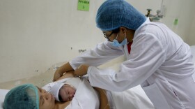 FILE - A doctor tends to mother Leni Bonto and baby Zairah inside the recovery room after Zairah was born on New Year's day Tuesday, Jan. 1, 2019, at Fabella Children's Hospital in suburban Quezon city northeast of Manila, Philippines. Zairah, the third child of Bonto, became the first baby born at the hospital on New Year's day.