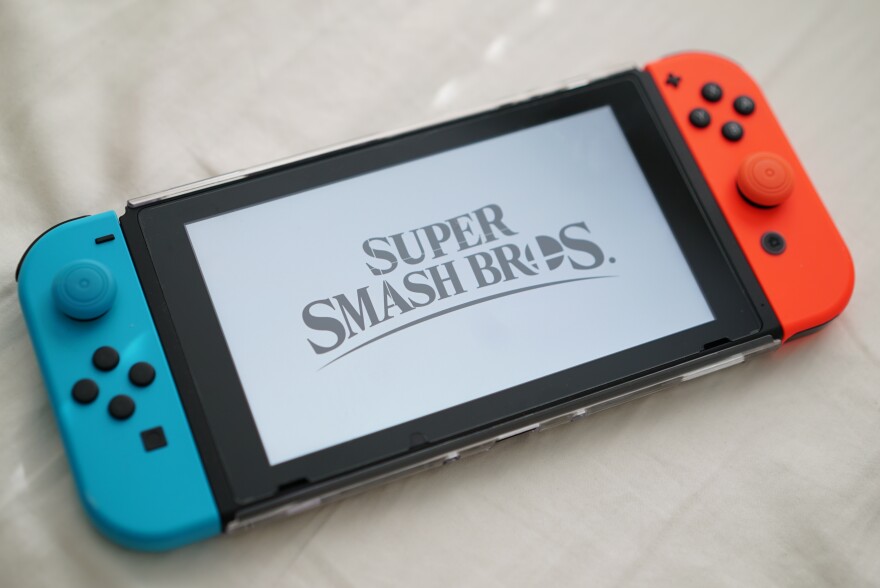 A Nintendo Switch displays the words, "Super Smash Bros."