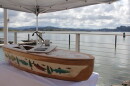 A canoe with salmon and tree designs next to water.