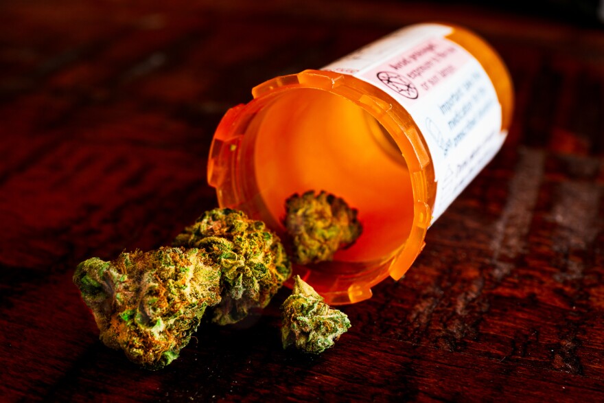 Close-Up of Dried Cannabis Flower Spilling Out of an Orange Pill Bottle on a Wooden Coffee Table