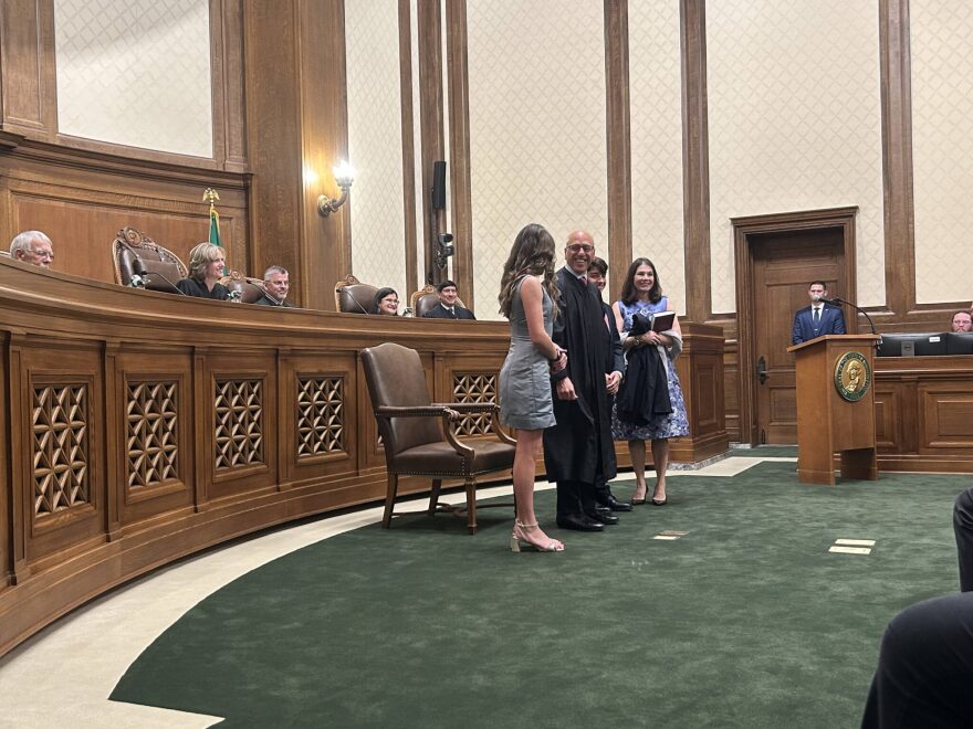 Washington state Supreme Court Justice Theo Angelis dons his robe alongside wife Kim and children Katherine and John as he is sworn in as a justice at the Temple of Justice on Monday, May 18, 2026, in Olympia.