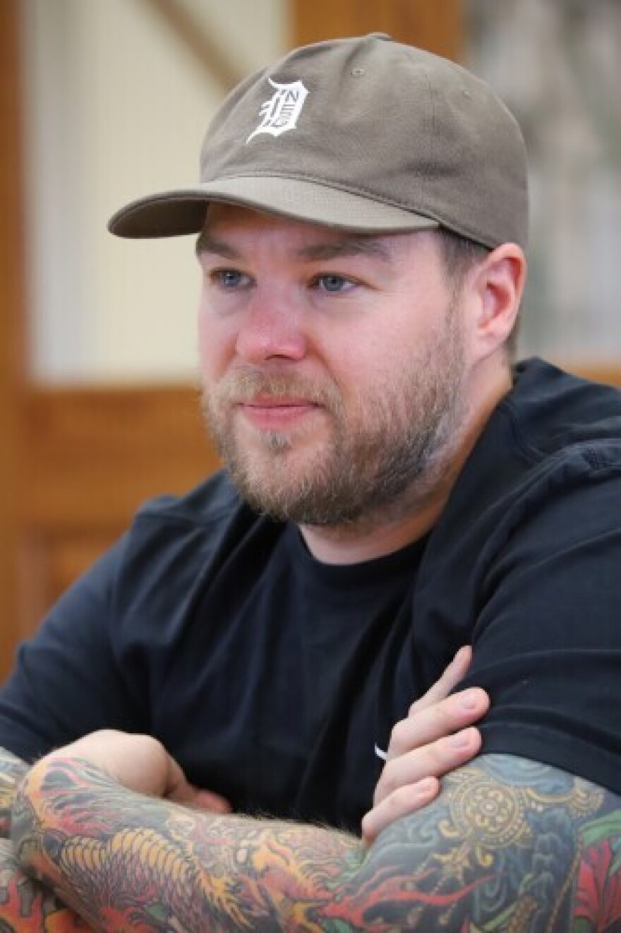 Christopher Booth sits at a table and listens to his mother speak.