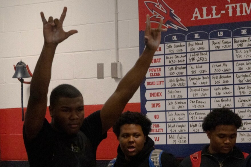La'Darius James (left), 18, raises his hands after setting a new deadlift personal best weight lifted. James's mother watched his completion.