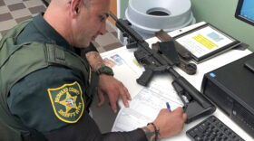 In this Feb. 16, 2018, photo provided by Ben Dickmann, a deputy at the Broward County sheriff's office in Ft. Lauderdale, Fla., processes paperwork to take possession of and destroy Dickmann's AR-style firearm. Dickmann decided to turn in his weapon after the shooting at Marjory Stoneman Douglas High School in nearby Parkland, Fla. (Ben Dickmann via AP)