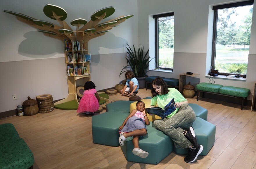 Quinn Gaul, a staff member at the newly opened Maplewood Nature Center, reads a book to 6-year-old Amber during a city of Rochester recreation camp. The center features interactive environmental education, a story corner, hands-on exhibits and programs designed to connect children with nature.