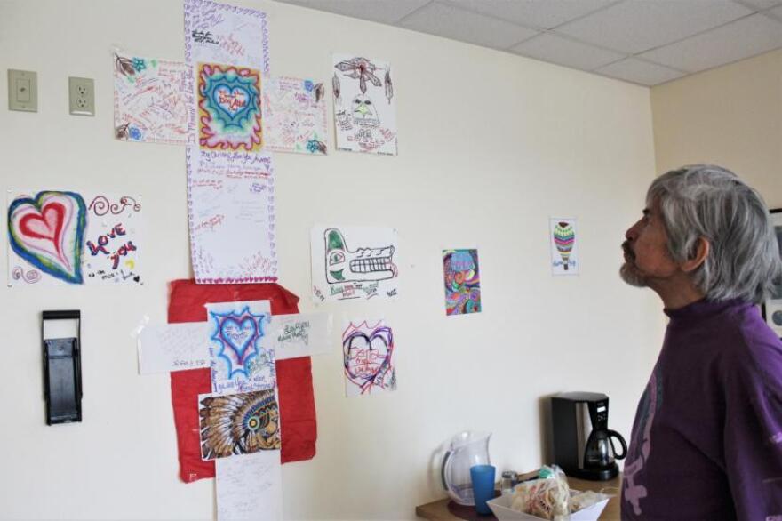 Matthew Fred Jr. examines a display Housing First residents made for fellow residents who have passed away. Fred says closing the facility would mean a loss of community for the tenants who live there. (Photo by Adelyn Baxter/KTOO)