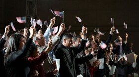 Group of immigrants waiving small United States flags.