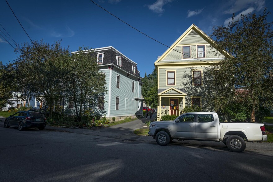 A white pickup truck is parked in front of two residential buildings