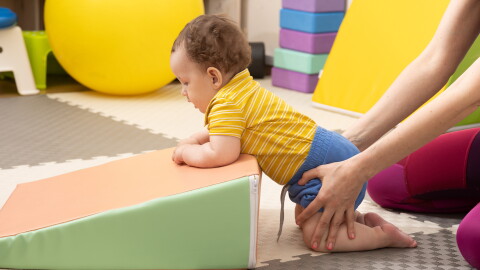 This stock photo shows an infant with muscle weakness receiving physical therapy.