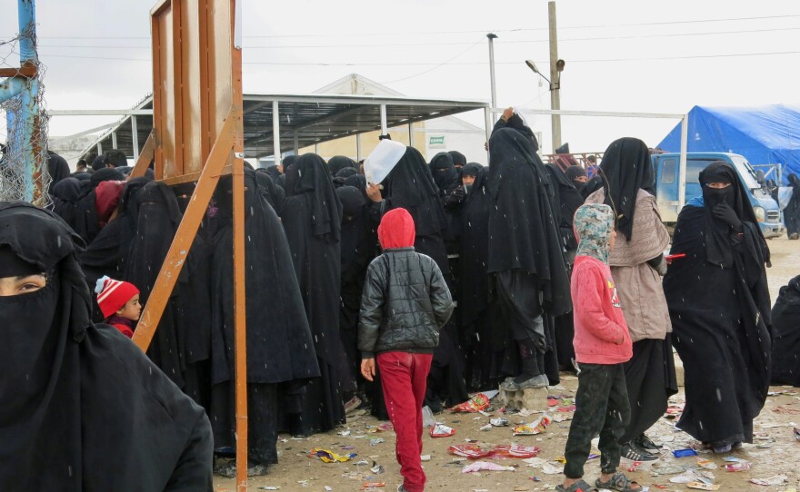 Women and children wait for distribution of food at the al-Hol camp in northeastern Syria. Most are family members of ISIS fighters, viewed by the region's Kurdish Syrian leadership as a potential danger. Iraq says it wants to bring back 30,000 of its citizens to place in Iraqi camps, but few are willing to return.