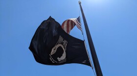 A POW/MIA flag flies with an American flag