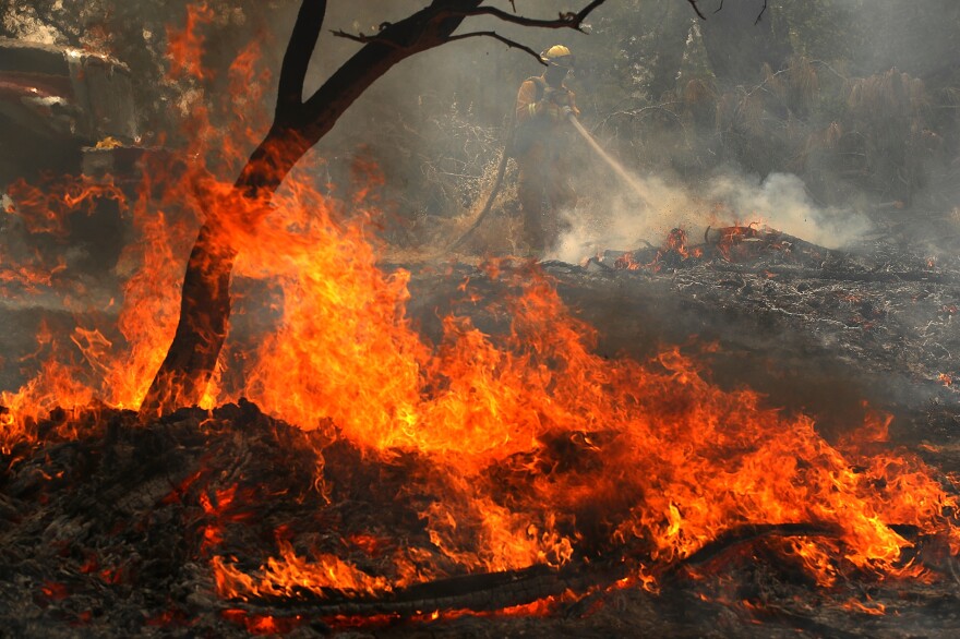 A Cal Fire firefighter mops up hot spots after the Carr Fire moved through the area on Saturday in Redding, Calif. The fire is 5 percent contained.