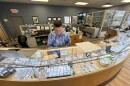 Geoffrey Demis, co-owner of Ferris Coin & Jewelry near Albany, reaches into his bullion display case at his shop a few miles from the state Capitol.