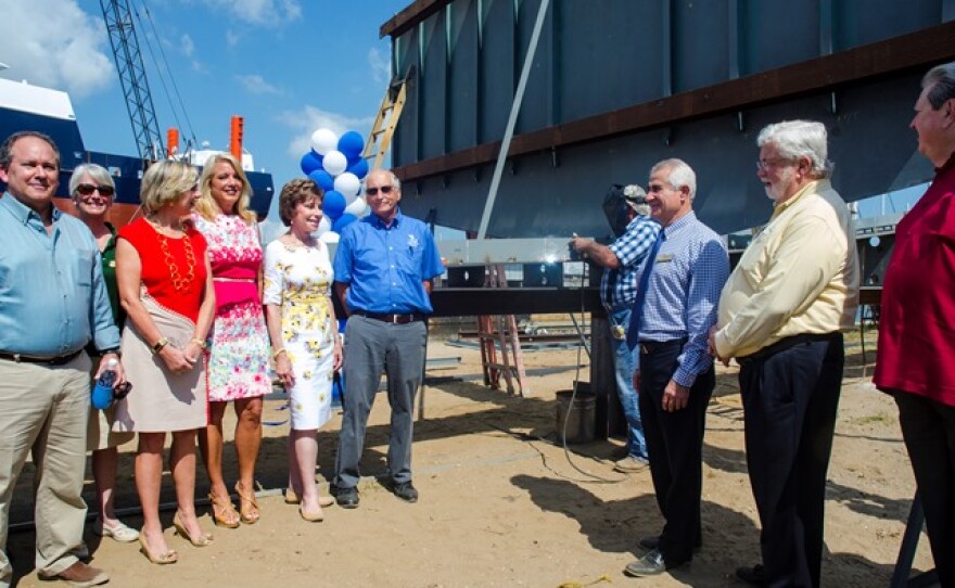 While officials from USF and FIO and local politicians look on, Duckworth Steel Boats owner Junior Duckworth (center, back) performs the ceremonial keel laying of the new research vessel.