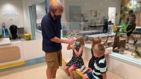 Jeremy Sander helps his daughter, Jordan, 5, take her temperature with an infrared thermometer at Lodgic Kids Camp in Champaign, Ill.
