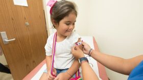 A health care worker places a bandage on a child after giving a vaccination shot. New federal guidance to reduce the number of recommended childhood vaccines from 17 to 11 comes as states are already charting their own course on vaccine policy.