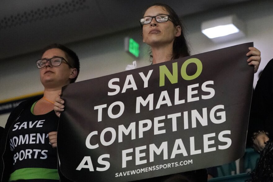 Protester hold signs as University of Pennsylvania transgender athlete Lia Thomas competes in the 200 freestyle finals at the NCAA Swimming and Diving Championships Friday, March 18, 2022, at Georgia Tech in Atlanta. Thomas finished tied for fifth place. (AP Photo/John Bazemore)