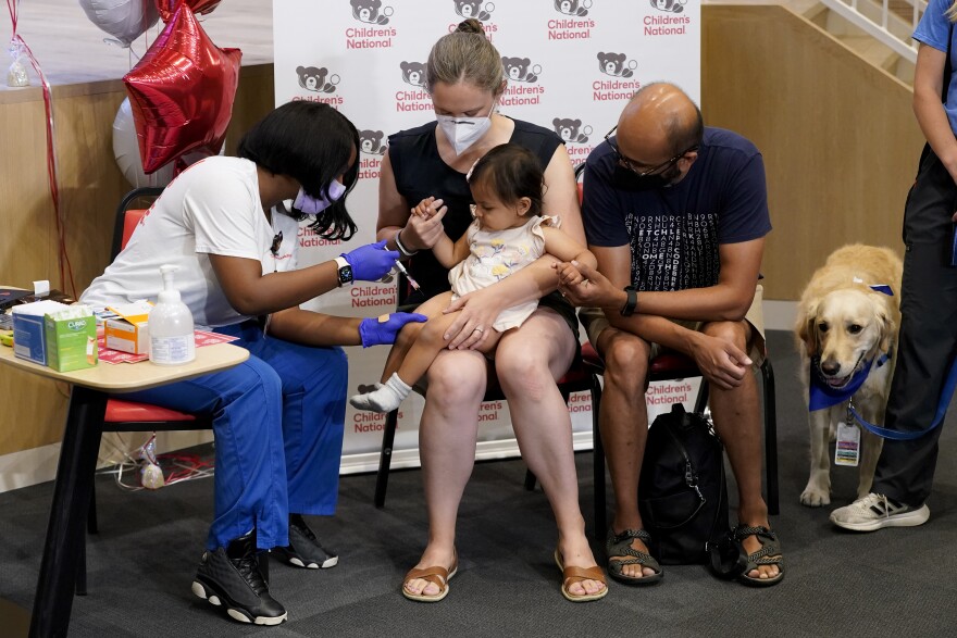 Vaccinating kids under 5 against COVID-19 has been slow across the United States since eligibility opened up a month ago. A small child sits next to their parents as a physician administers a COVID-19 vaccine.