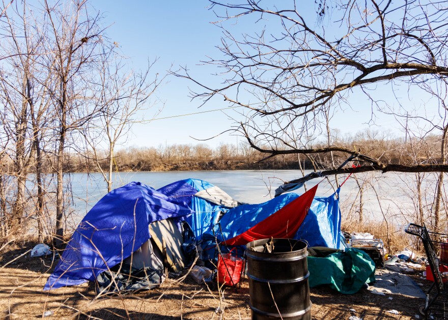 A tent structure is set up on a path. A lake is behind it.