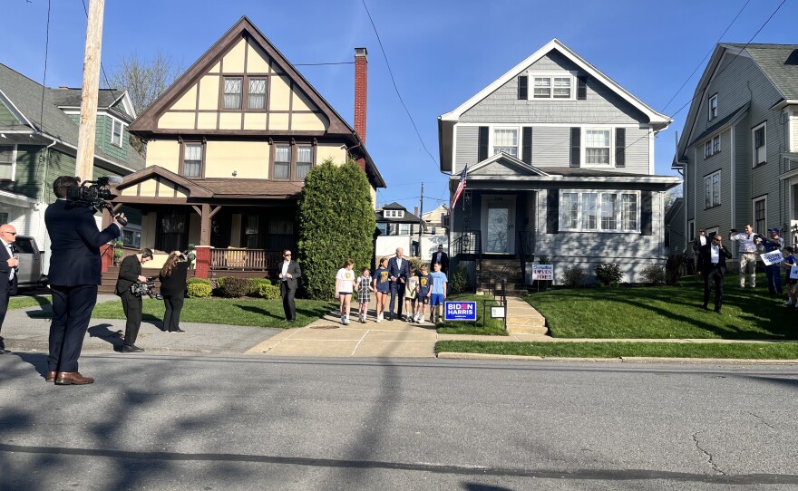 President Joe Biden walks out of his childhood home hand-in-hand with a group of young children.