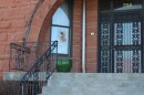 Brick building with gated door at the entrance and a broken window to the left