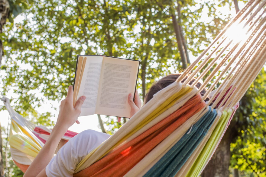 a person lays in a hammock with an open book