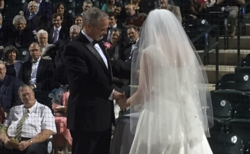 Mr. and Mrs. Mark Cain sign their wedding certificate before friends at the Columbia Fireflies ball park.