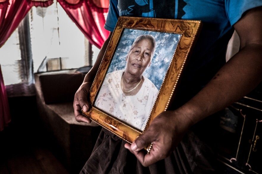 Mesak holds a picture of his mother, Alfrida, who died in 2012.