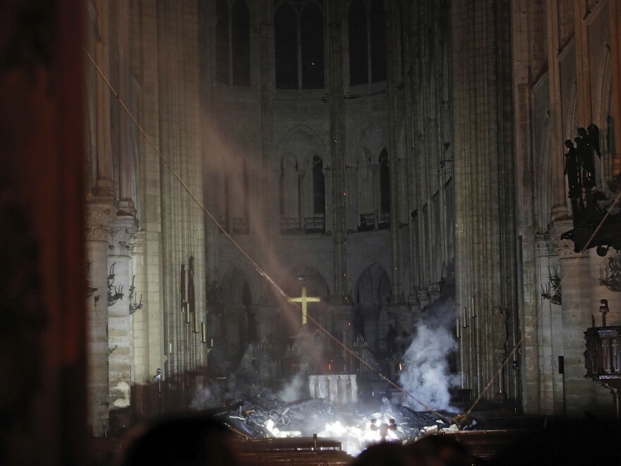 Smoke rises in front of the cross in the interior of Notre Dame Cathedral in Paris. A catastrophic fire engulfed the cathedral on Monday, as tourists and Parisians looked on from the streets below.