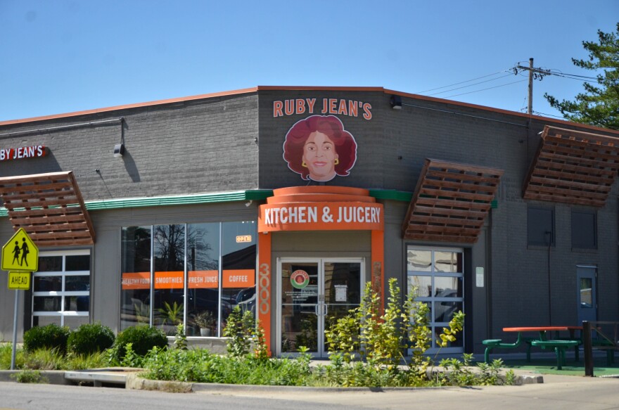 A business called Ruby Jean's Juicery stands on a street corner, with tables in the front.