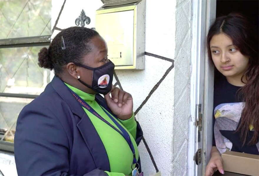 Broward County Public Schools social worker Lilia Francois gives Marjory a laptop for online classes during a visit to her home on Dec. 3, 2020. Marjory's mother, María, said the family has not had a computer or consistent access to the internet during the pandemic. Florida Public Media is not using their last names to protect the family's privacy. Photo: David Diez/South Florida PBS