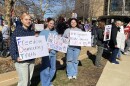 Three young women hold protest signs in Uptown Normal