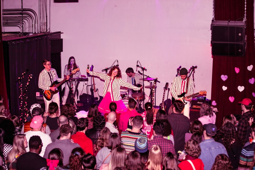 A crowd of people watch the band Ramona and the Sometimes perform at xBk Live in coordinating striped shirts.