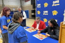 Terry Madigan, Tournament of Roses president, and Esmeralda Rocha Lozano, Clovis High music director, sign Rose Parade posters for band students.