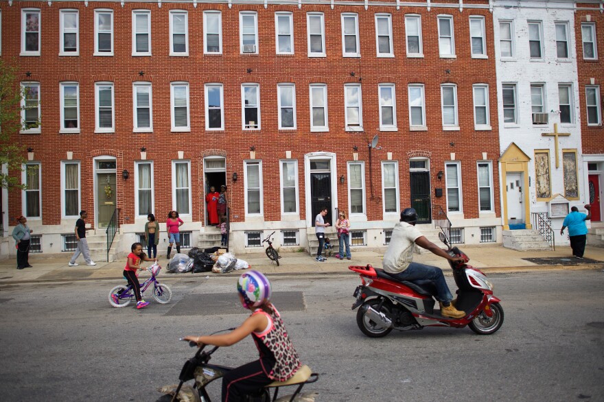 Neighborhood children ride bicycles in the street on Tuesday afternoon in Baltimore.