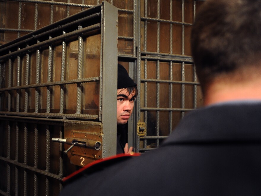 A police officer locks up an illegal migrant from Uzbekistan at a police station in Moscow's Kazansky railway station, in 2012.