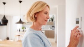 Woman adjusting thermostat.
